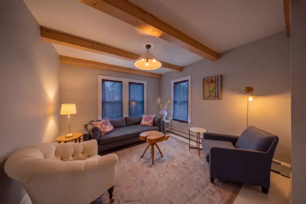 Warm modern living room with exposed beams, comfortable seating, and ambient lighting.