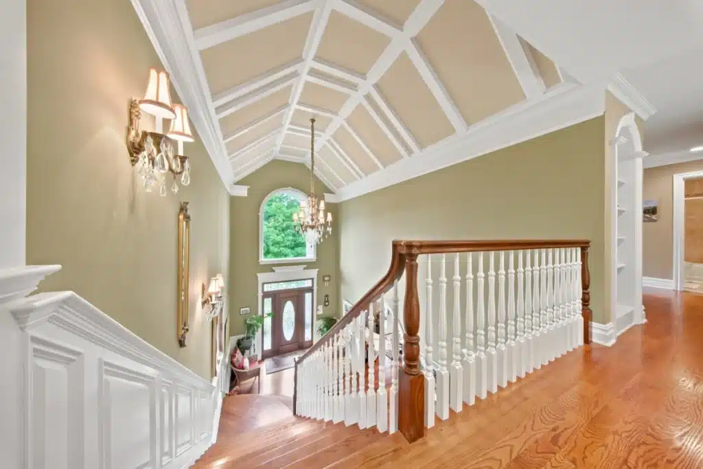 Elegant foyer with vaulted ceiling, wooden staircase, and arched window.
