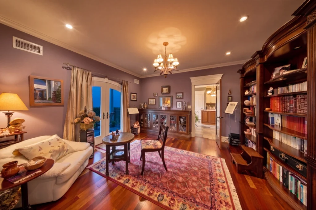 Elegant purple bedroom with hardwood floors, built-in bookshelves, and formal seating area.