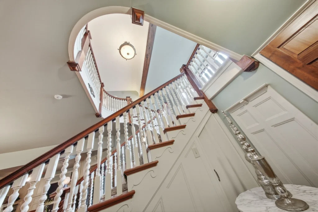Wooden staircase with white balusters ascending toward bright upper landing.