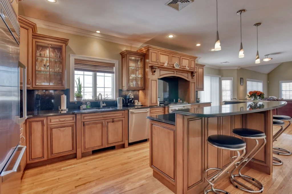 Spacious kitchen with wooden cabinets, island seating, and stainless steel appliances.